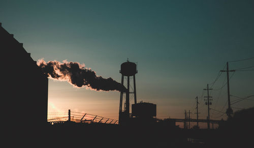 Low angle view of silhouette of storage tank at sunset