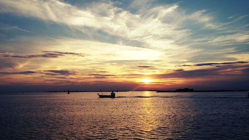 Silhouette boat sailing in sea against sky during sunset