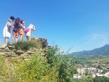 Low angle view of women looking at landscape against sky during sunny day