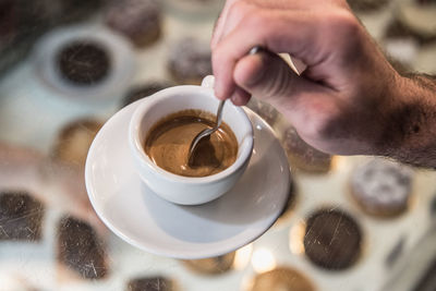 Cropped hand stirring coffee on table