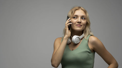 Portrait of young woman with arms crossed standing against gray background