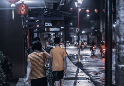 Rear view of people standing on street at night