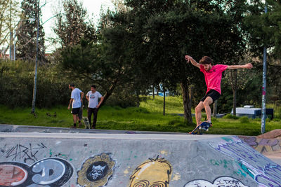 Rear view of people jumping against trees