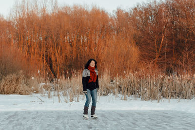 Full length portrait of young woman standing in snow