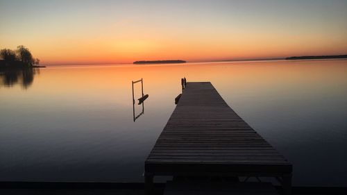 Pier over lake against sky during sunset