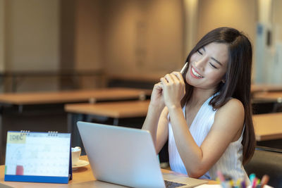 Young woman using mobile phone while sitting on table