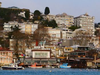 Sailboats moored on sea by buildings in city