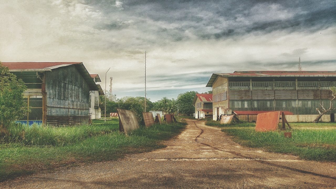 building exterior, sky, architecture, cloud - sky, built structure, cloudy, house, the way forward, transportation, weather, overcast, cloud, residential structure, dirt road, vanishing point, diminishing perspective, road, day, field, nature