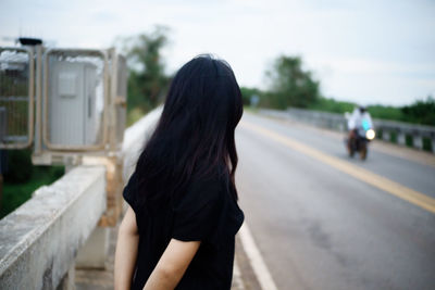 Side view of woman standing on road in city
