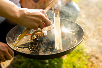 Close-up of hands kindling a fire with natural material