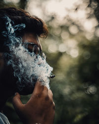 Portrait of man holding cigarette outdoors