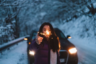 Woman lighting sparkles during winter while on a road trip in the mountains.