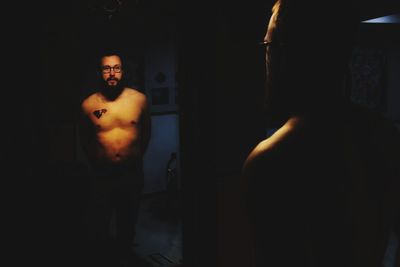 High angle view of shirtless man standing in illuminated room