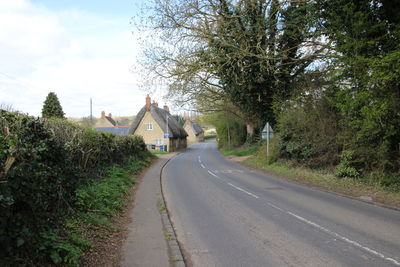 Road amidst trees in city against sky