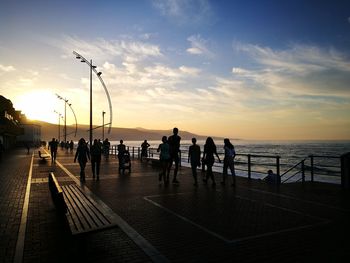 People walking on promenade during sunset