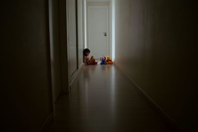 Girl with toys sitting in corridor