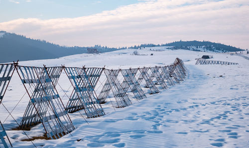 Snow covered fence by snowcapped mountain against sky