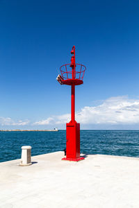 Lighthouse by sea against blue sky