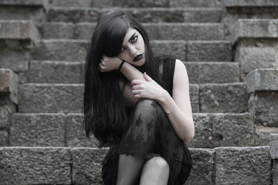 Portrait of a young woman against brick wall