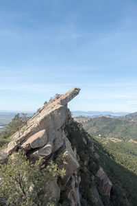 Driftwood on rock against sky