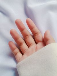 Cropped hand of person on bed at home