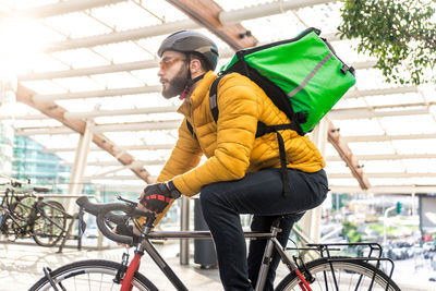 Man standing with bicycle on street in city