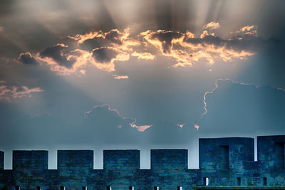 Low angle view of surrounding wall against back lit sky