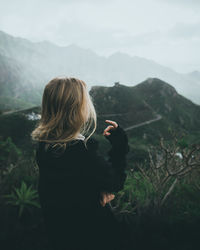 Woman looking away while standing against mountain range