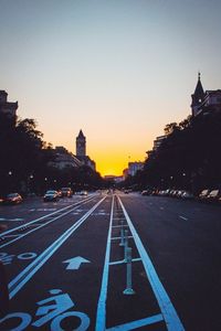 Cars on street amidst buildings at sunset