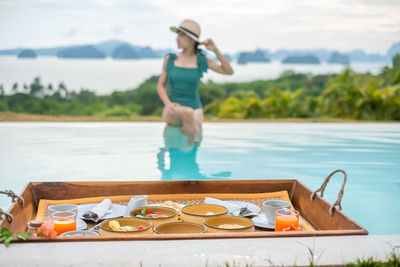 Full length of woman having food at swimming pool