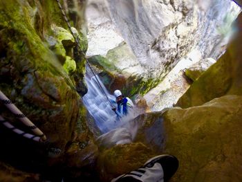 High angle view of woman rock climbing by waterfall