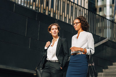 Businesswomen walking on steps against wall