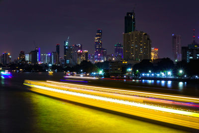 Light trails on illuminated buildings in city at night