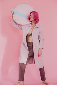 Woman standing against pink wall