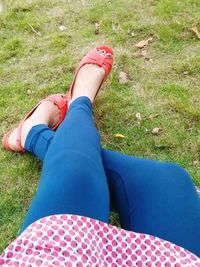 Low section of woman relaxing on grassy field