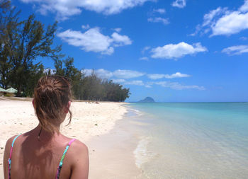 Rear view of woman looking at sea against sky on a tropical pristine beach on mauritius island