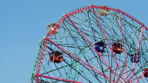 Low angle view of ferris wheel against blue sky