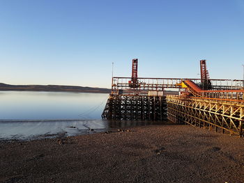 Commercial dock at river against clear blue sky