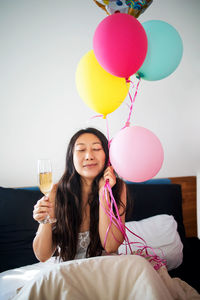 Young woman holding balloons in bedroom
