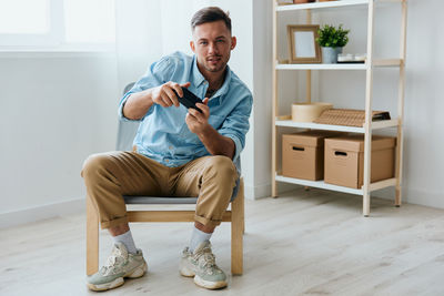 Portrait of young man using mobile phone while sitting at home
