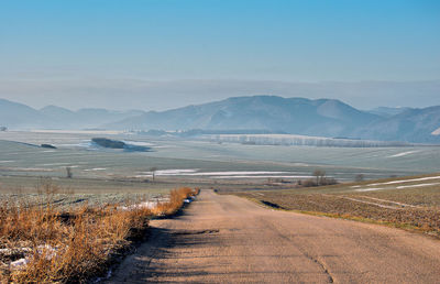 Scenic view of road by lake against sky