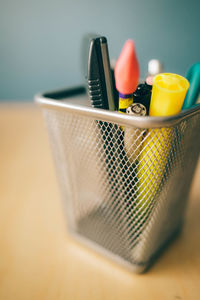 Close-up of pens in desk organizer on wooden table