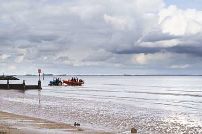 A tractor towing a rib boat out of the water at cleethorpes beach