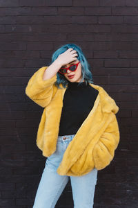 Young woman standing against yellow wall