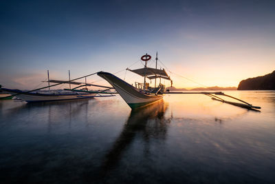 Ship moored in sea against sky during sunset