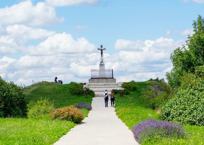 Rear view of people walking on plants against sky