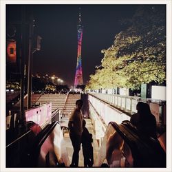 People walking in city lit up against sky