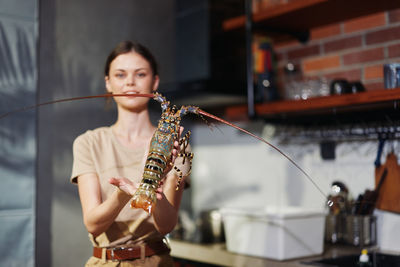 Portrait of young woman blowing bubbles while standing at home