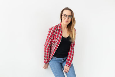 Portrait of young woman standing against white background