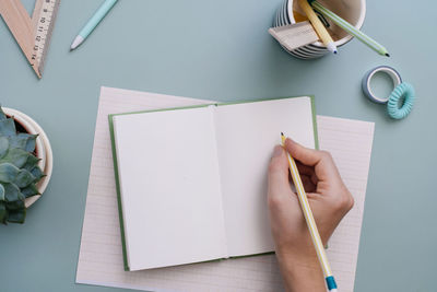 Cropped hands writing in book on table